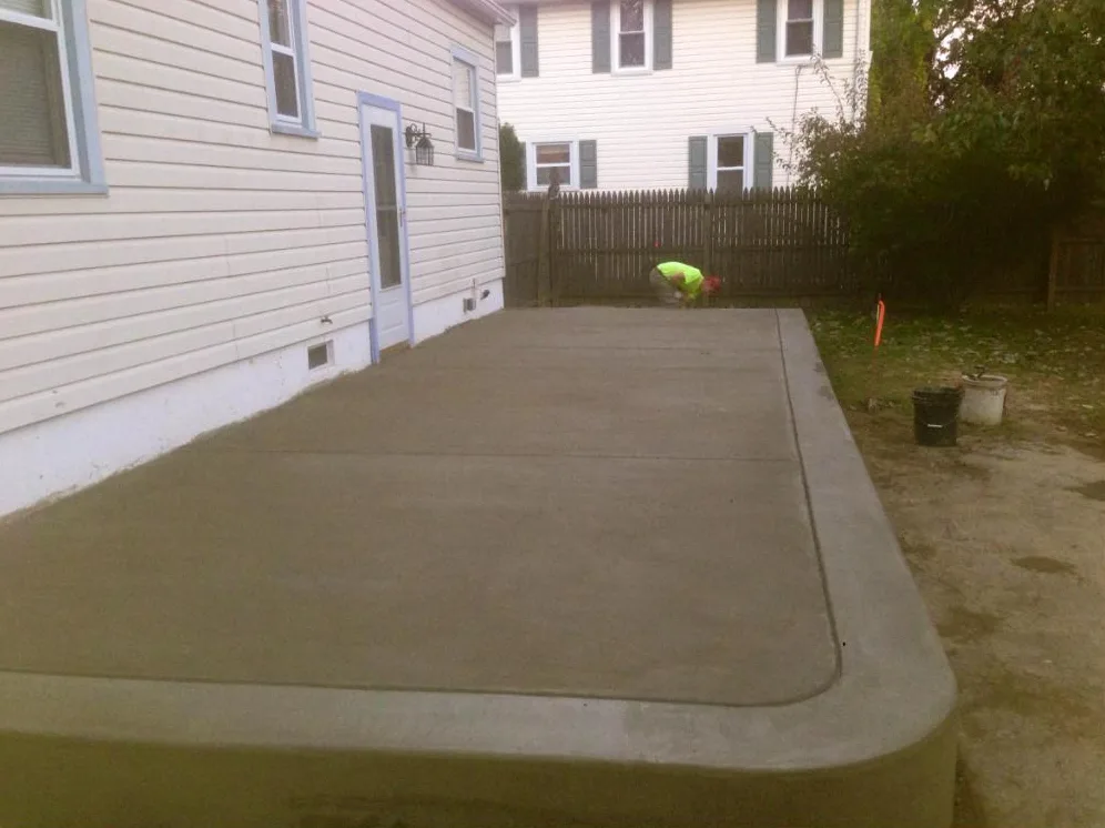 Newly poured concrete patio slab with a smooth tooled edge beside a house