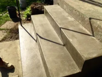 Poured concrete steps with a black metal handrail