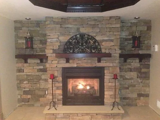 Stacked stone veneer fireplace with a wood mantel