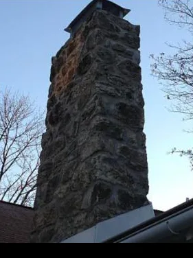 Tall fieldstone chimney against a winter sky